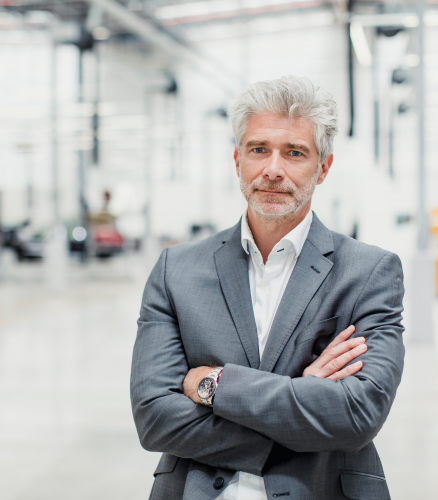 A businessman in a car factory that exemplifies our ideal customer for our advanced ai for autonomous vehicles